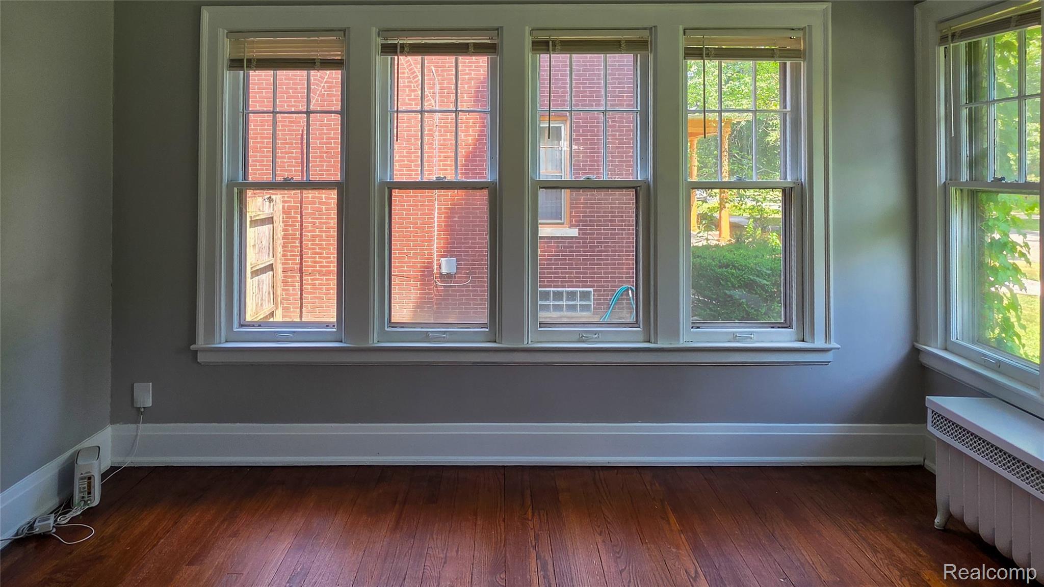 16715 Edinborough Road Detroit, MI 48219 - Photo 5 of 21 Hardwood flooring, painted walls, white trim, multiple windows with grid patterns, and a built-in radiator cover