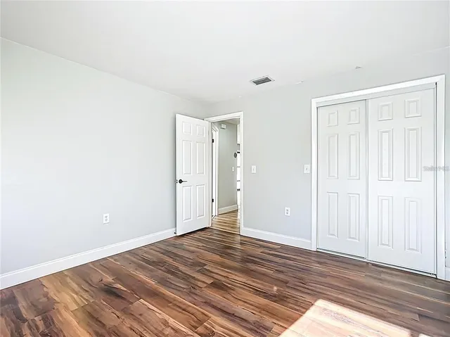 an empty room with wooden floor & closet area