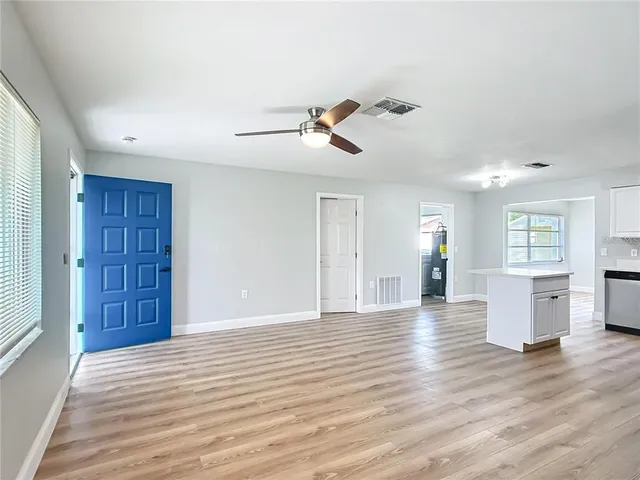 a view of an empty room with window and wooden floor
