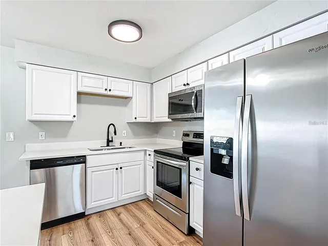 a kitchen with cabinets stainless steel appliances and a sink