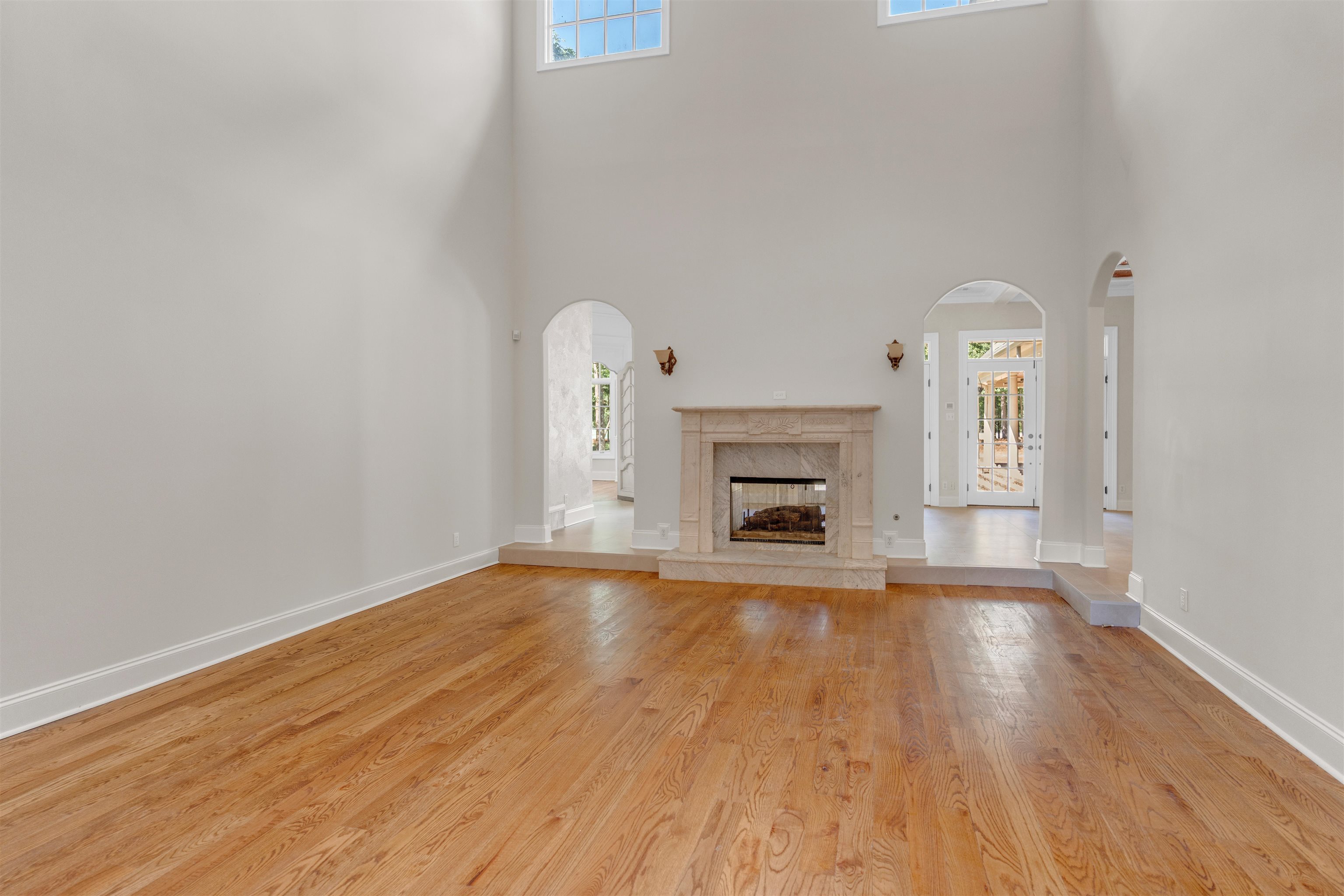 815 Dent Road Eads, TN 38028 - Photo 7 of 40 Unfurnished living room featuring a premium fireplace, light wood finished floors, a towering ceiling, and arched walkways