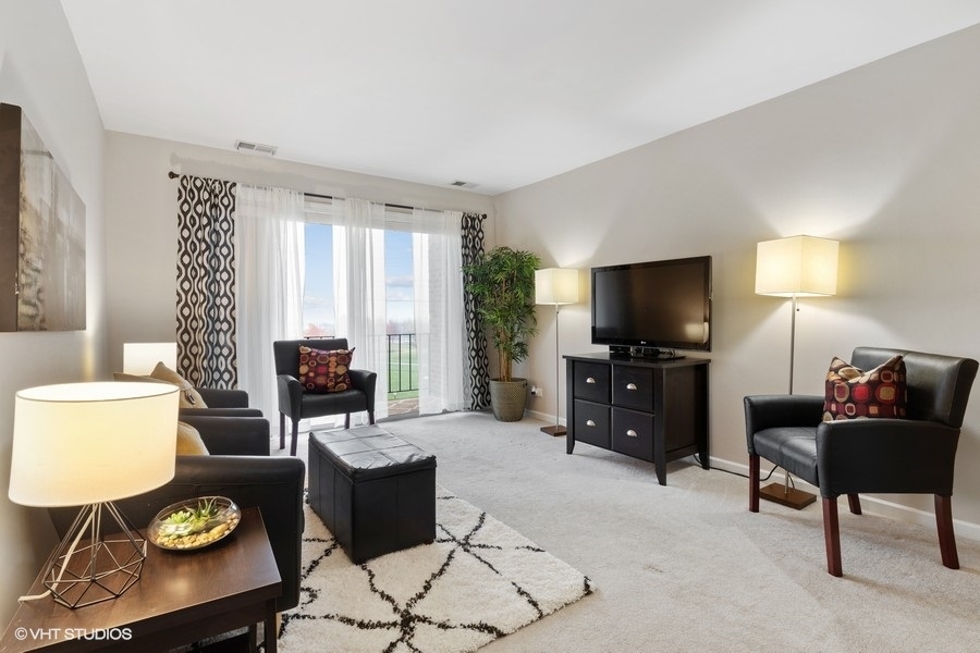 725 West Huntington Commons Road, Unit 416 Mount Prospect, IL 60056 - Photo 2 of 17 a living room with furniture and a flat screen tv