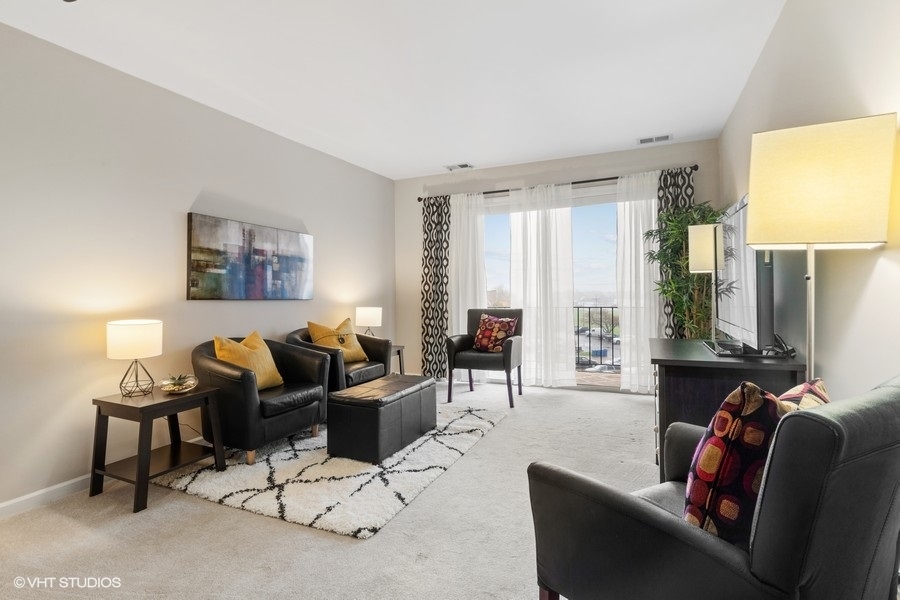 725 West Huntington Commons Road, Unit 416 Mount Prospect, IL 60056 - Photo 3 of 17 a living room with furniture and a large window