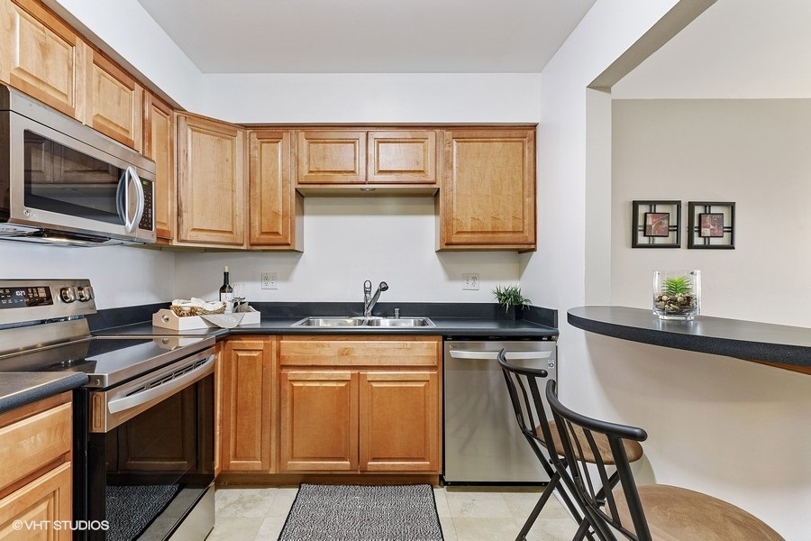 725 West Huntington Commons Road, Unit 416 Mount Prospect, IL 60056 - Photo 5 of 17 a kitchen with stainless steel appliances granite countertop a stove a sink a microwave and cabinets