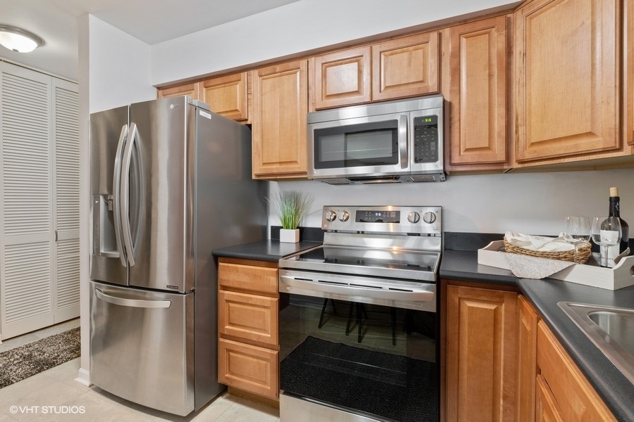 725 West Huntington Commons Road, Unit 416 Mount Prospect, IL 60056 - Photo 6 of 17 a kitchen with stainless steel appliances granite countertop a refrigerator stove and microwave