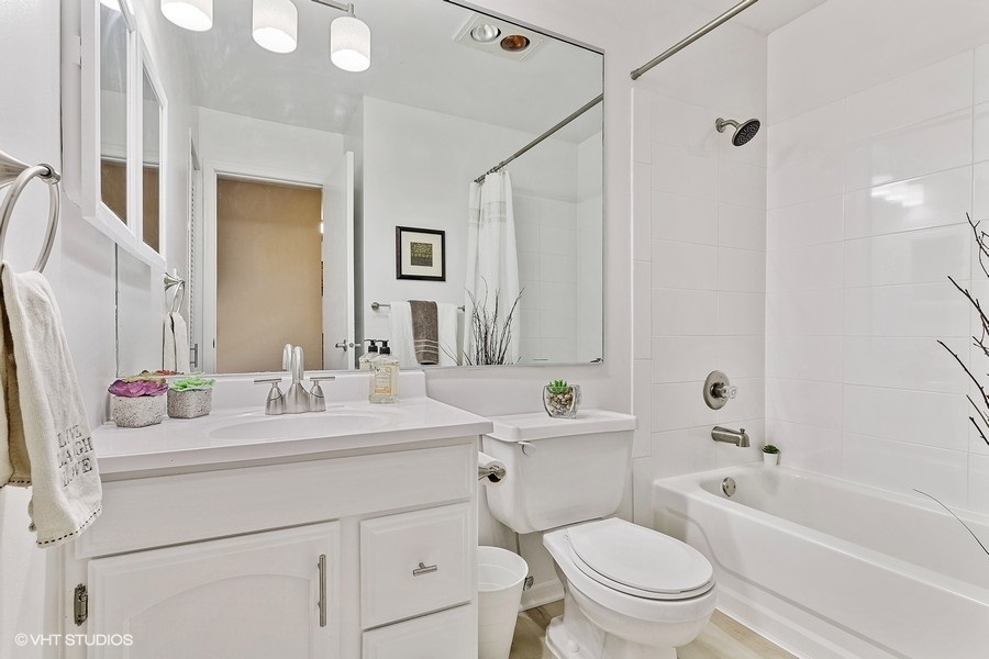 725 West Huntington Commons Road, Unit 416 Mount Prospect, IL 60056 - Photo 10 of 17 a bathroom with a sink a toilet a mirror a vanity a bathtub and shower