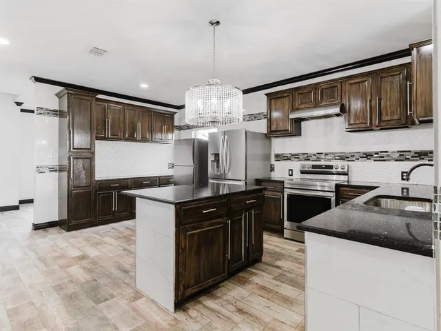 a kitchen with stainless steel appliances granite countertop a sink stove and refrigerator