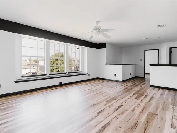 a view of an empty room with a window and wooden floor