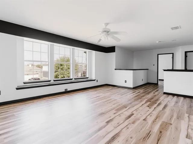 a view of an empty room with a window and wooden floor