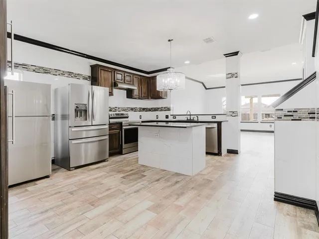 a kitchen with stainless steel appliances granite countertop a stove top oven and refrigerator
