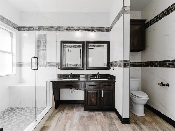a bathroom with a double vanity sink a mirror and a toilet
