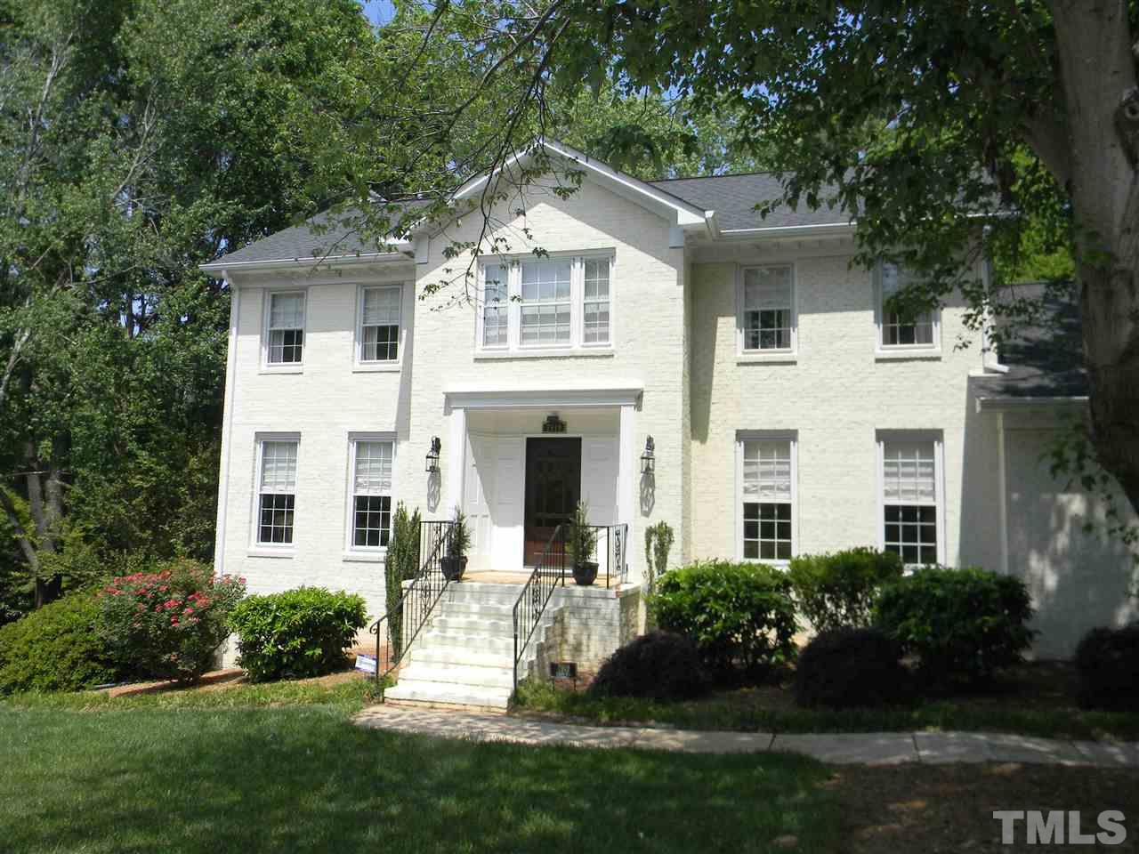 a front view of a white house with a yard and potted plants