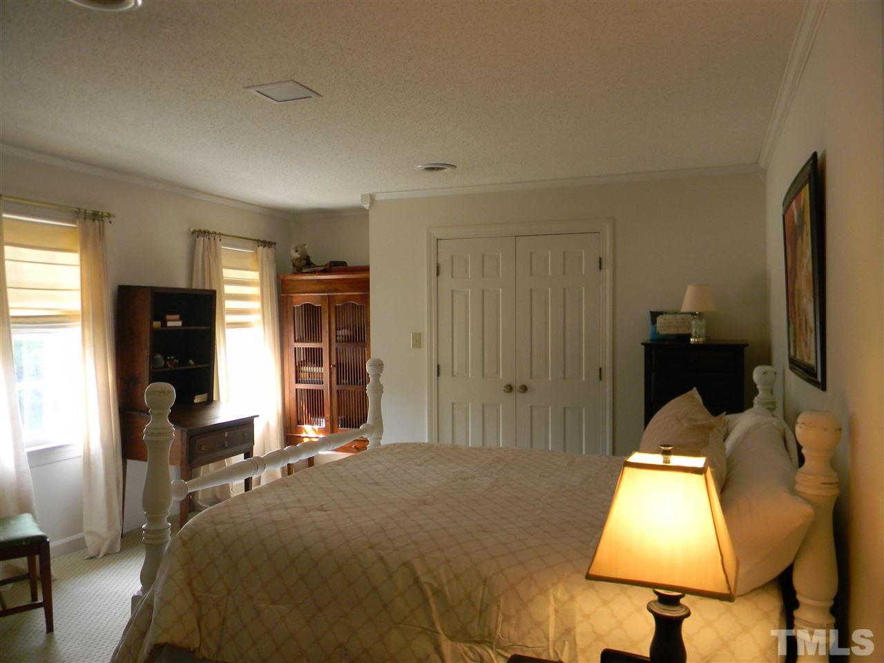 7919 Harps Mill Road Raleigh, NC 27615 - Photo 11 of 29 a bed room with a bed and a flat tv screen on dresser