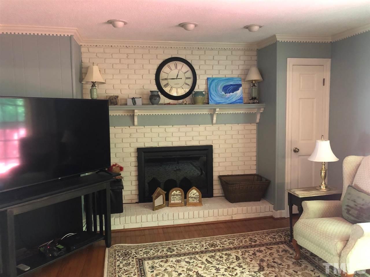 7919 Harps Mill Road Raleigh, NC 27615 - Photo 7 of 29 a living room with furniture a clock and a fireplace