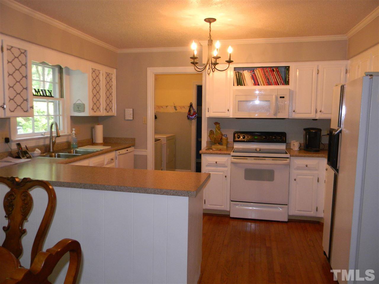 7919 Harps Mill Road Raleigh, NC 27615 - Photo 10 of 29 a kitchen that has a lot of cabinets a island a stove a refrigerator and wooden floor