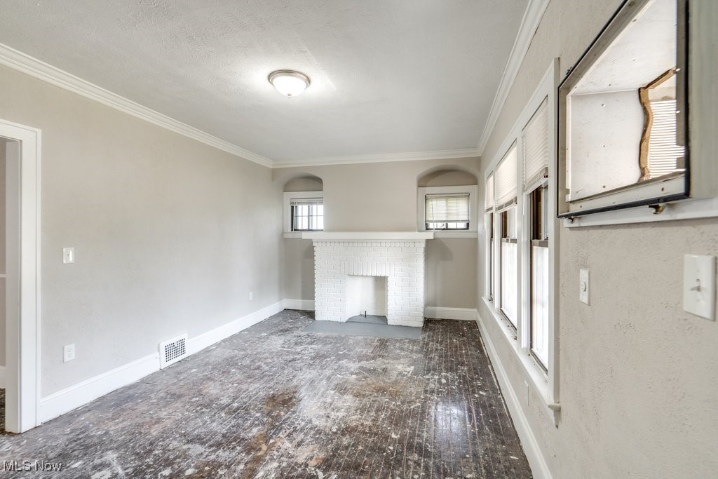 1618 Catalpa Road Cleveland, OH 44112 - Photo 28 of 33 Unfurnished living room with ornamental molding, a brick fireplace, hardwood / wood-style flooring, and a textured ceiling