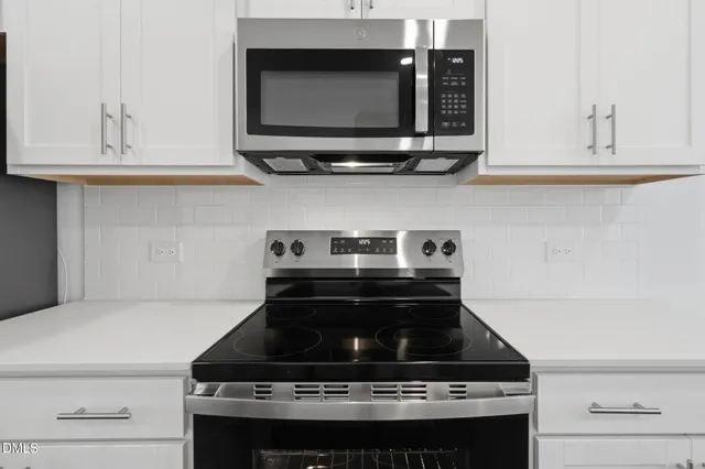 a kitchen with stainless steel appliances white cabinets and a stove top oven