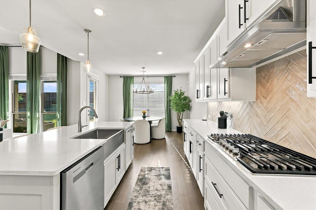 137 Chisos Court Rhome, TX 76078 - Photo 15 of 40 Kitchen featuring white shaker cabinetry, stainless steel appliances, wood-finish flooring, and a herringbone-patterned backsplash
