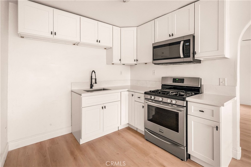 407 4th Street Bakersfield, CA 93304 - Photo 9 of 31 a kitchen with stainless steel appliances granite countertop white cabinets a sink a stove a microwave and view living room