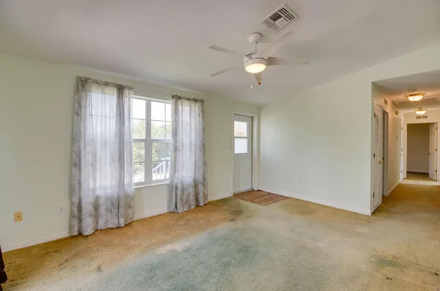 a view of an empty room with chandelier fan and fire place