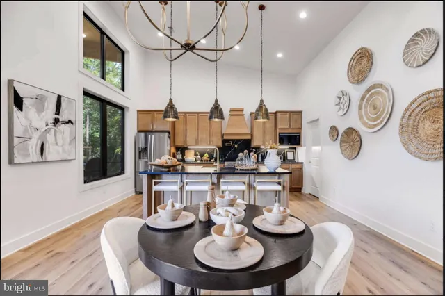 a kitchen with stainless steel appliances kitchen island granite countertop a stove a sink a dining table and chairs with wooden floor