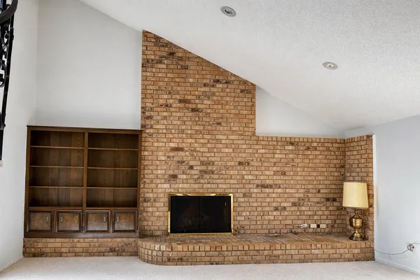 a view of an empty room with wooden floor and a fireplace