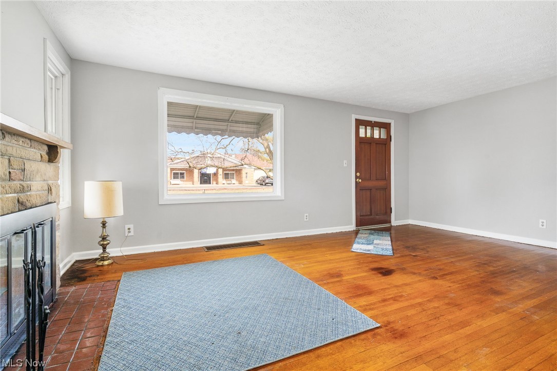 2942 17th Street Northwest Canton, OH 44708 - Photo 7 of 25 Sitting room with dark wood-type flooring, a textured ceiling, and a stone fireplace