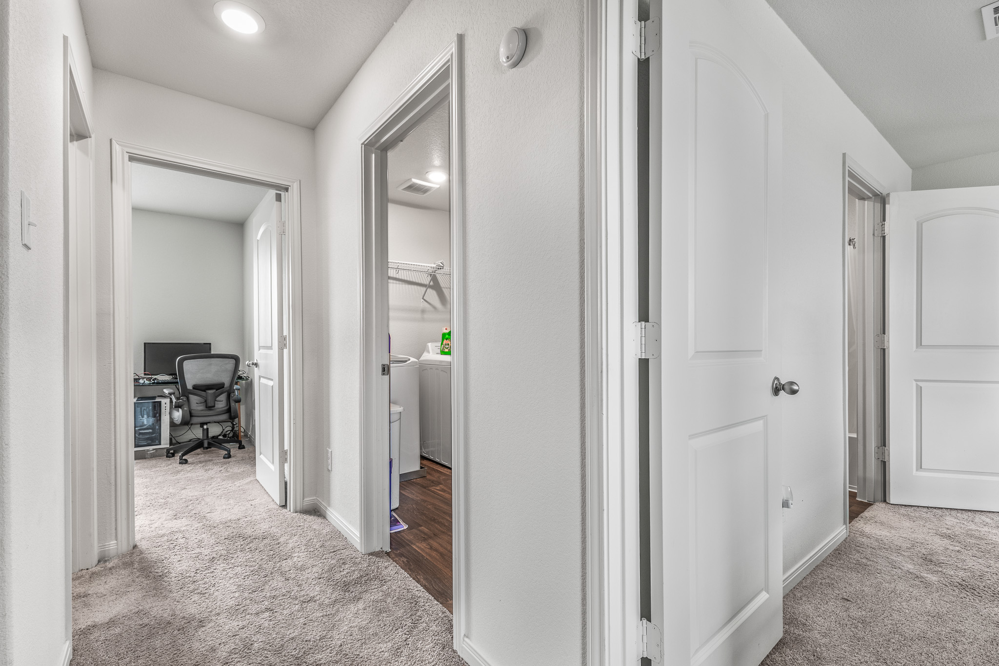 304 Hyacinth Way, Unit #7K Jarrell, TX 76537 - Photo 11 of 26 A well-lit hallway connects functional spaces, showcasing plush carpeting and recessed lighting.