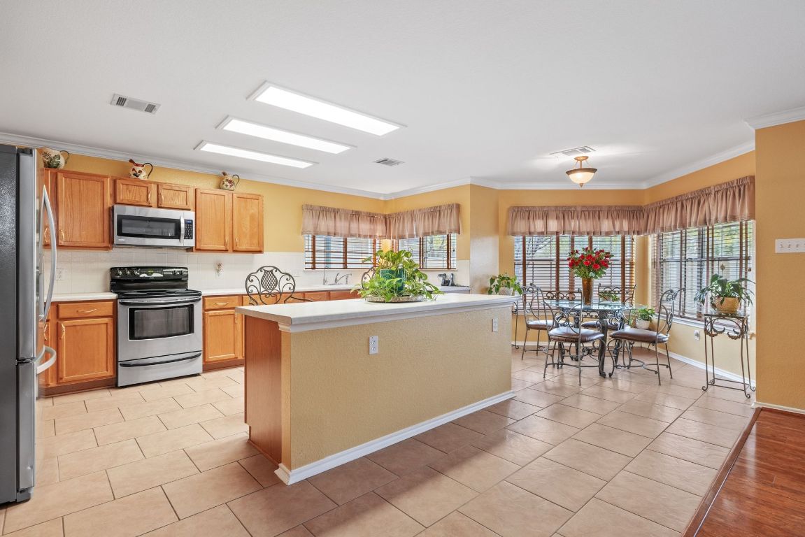 2210 Rachel Ridge Cedar Park, TX 78613 - Photo 13 of 40 a room with stainless steel appliances kitchen island granite countertop a stove a sink a dining table and chairs with the view of kitchen