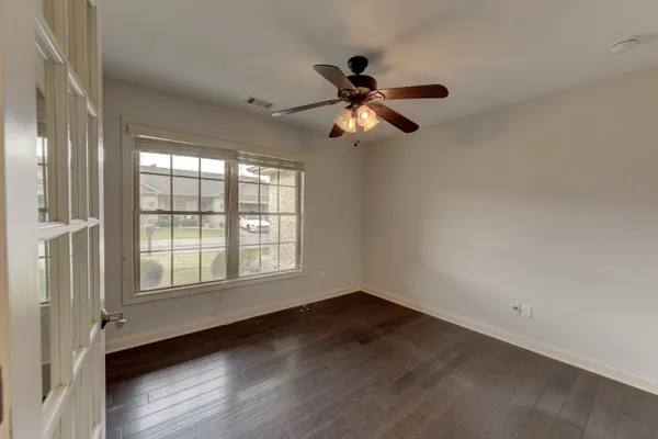 an empty room with wooden floor fan and windows