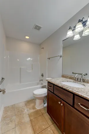 a bathroom with a granite countertop sink a toilet and bathtub