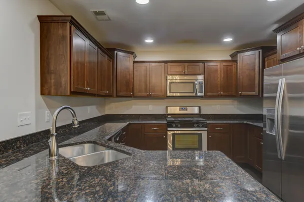 a kitchen with stainless steel appliances granite countertop a sink stove and refrigerator