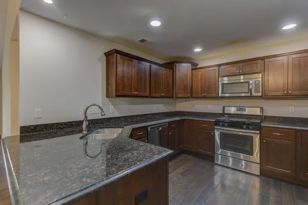 a kitchen with stainless steel appliances granite countertop a sink stove and microwave