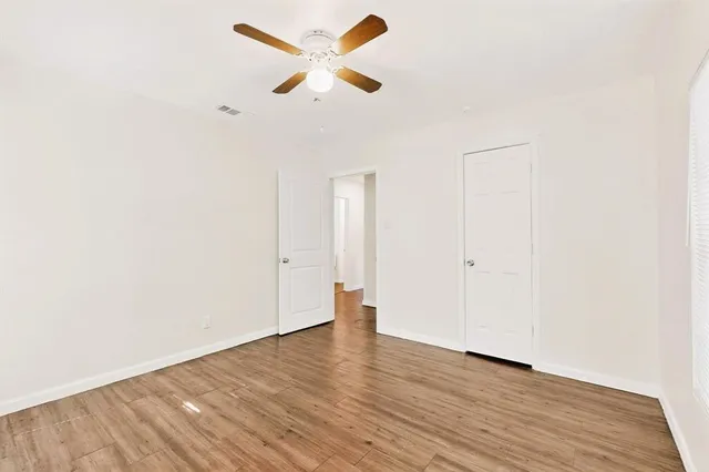an empty room with wooden floor and a ceiling fan