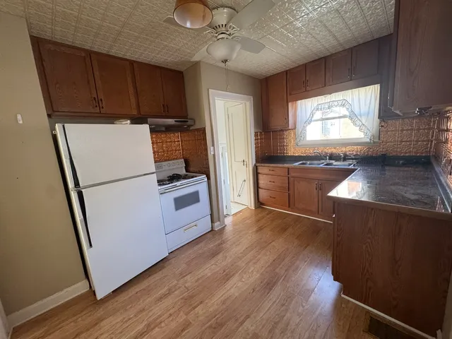 a kitchen with granite countertop wooden floors appliances a sink and a window