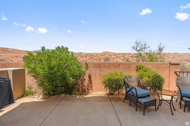4257 Razor Drive Washington, UT 84780 - Photo 47 of 58 Concrete patio with a block privacy wall, desert landscaping, and distant mountain scenery
