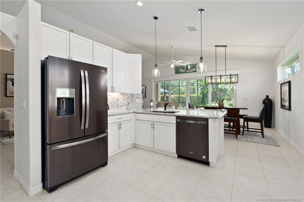 2688 Southeast Castle Pine Place Stuart, FL 34997 - Photo 20 of 49 a kitchen with stainless steel appliances granite countertop a refrigerator a sink a stove and chairs
