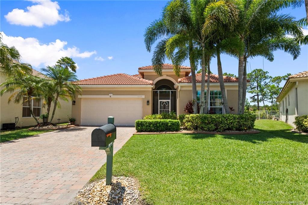 2688 Southeast Castle Pine Place Stuart, FL 34997 - Photo 4 of 49 a front view of a house with a garden and yard