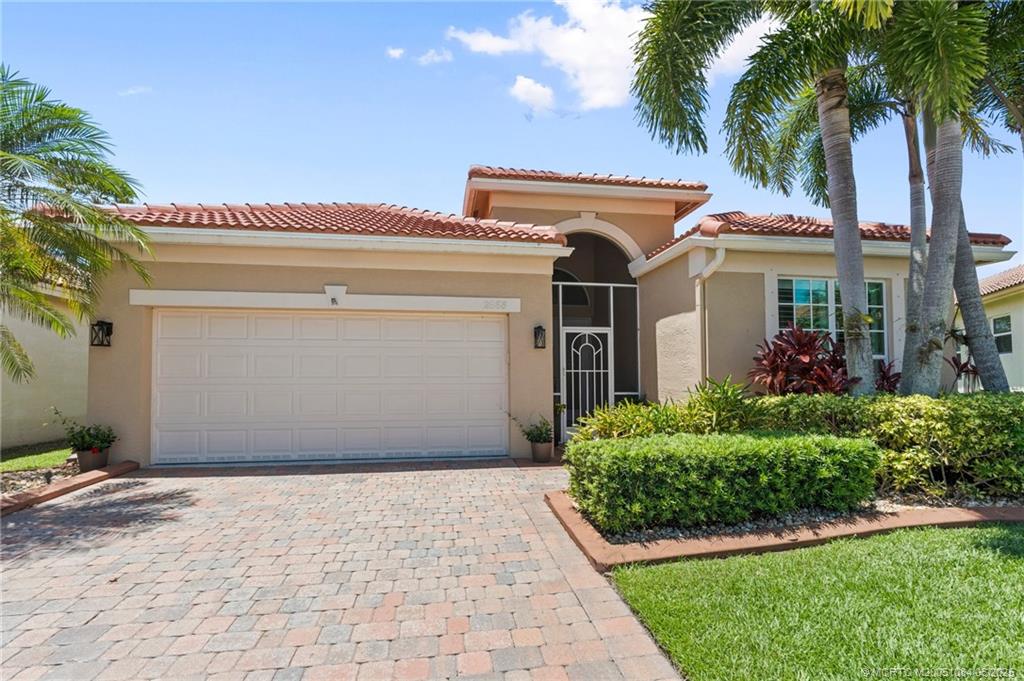 2688 Southeast Castle Pine Place Stuart, FL 34997 - Photo 5 of 49 a front view of a house with a yard and potted plants