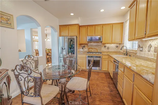 a kitchen with kitchen island granite countertop a table chairs sink and cabinets