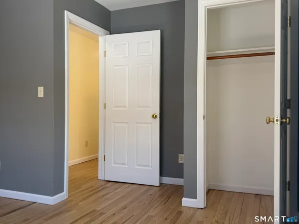 a view of an empty room with wooden floor and closet