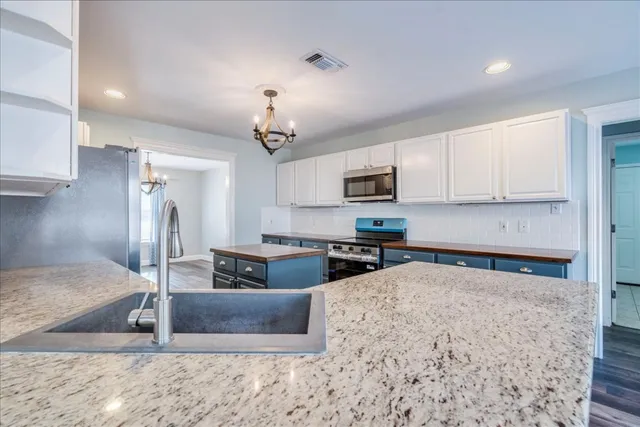 a kitchen with stainless steel appliances granite countertop a sink a stove counter space and cabinets