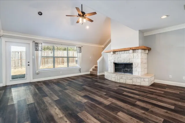 a view of an empty room with wooden floor fireplace and a window