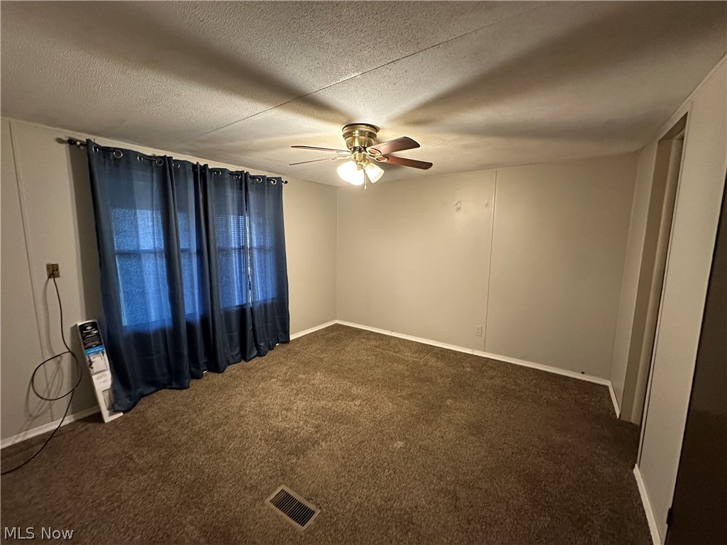 550 Rocky Point Road Vincent, OH 45784 - Photo 8 of 14 Spare room with a ceiling fan, dark carpet, and a textured ceiling