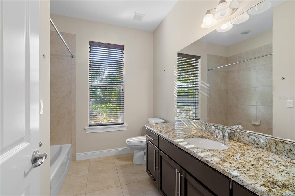 4117 Southeast 21st Street Ocala, FL 34471 - Photo 23 of 38 a bathroom with a granite countertop sink a large mirror and a bathtub