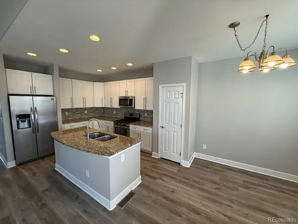 a kitchen with stainless steel appliances granite countertop a sink refrigerator and cabinets