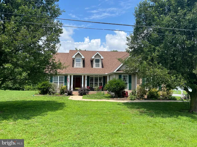 a front view of a house with garden and trees