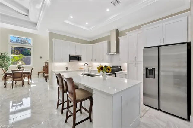 a kitchen with stainless steel appliances granite countertop a refrigerator a stove a sink a dining table and chairs