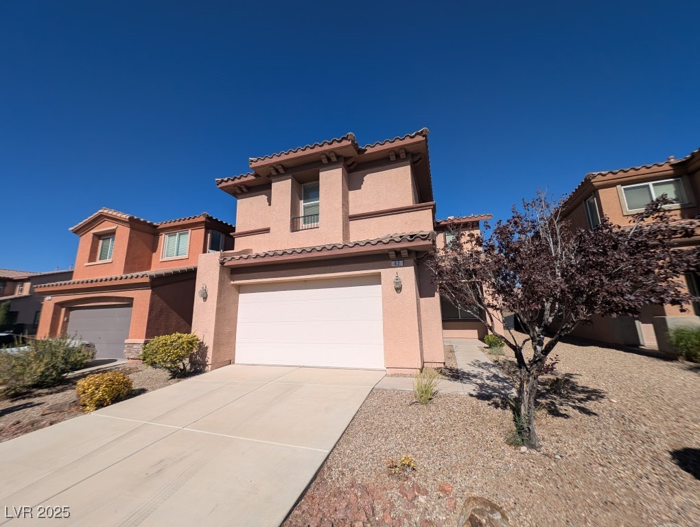 Mediterranean / spanish home featuring stucco siding, concrete driveway, a garage, and a tile roof