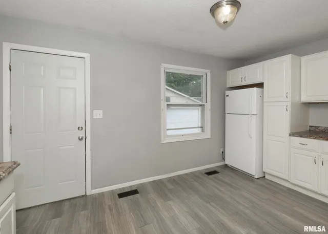 an empty room with wooden floor cabinet and windows